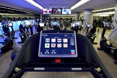 Holmes Place Club Gym with exercise equipment featuring interactive screens on treadmills at Hotel Cascais Miragem