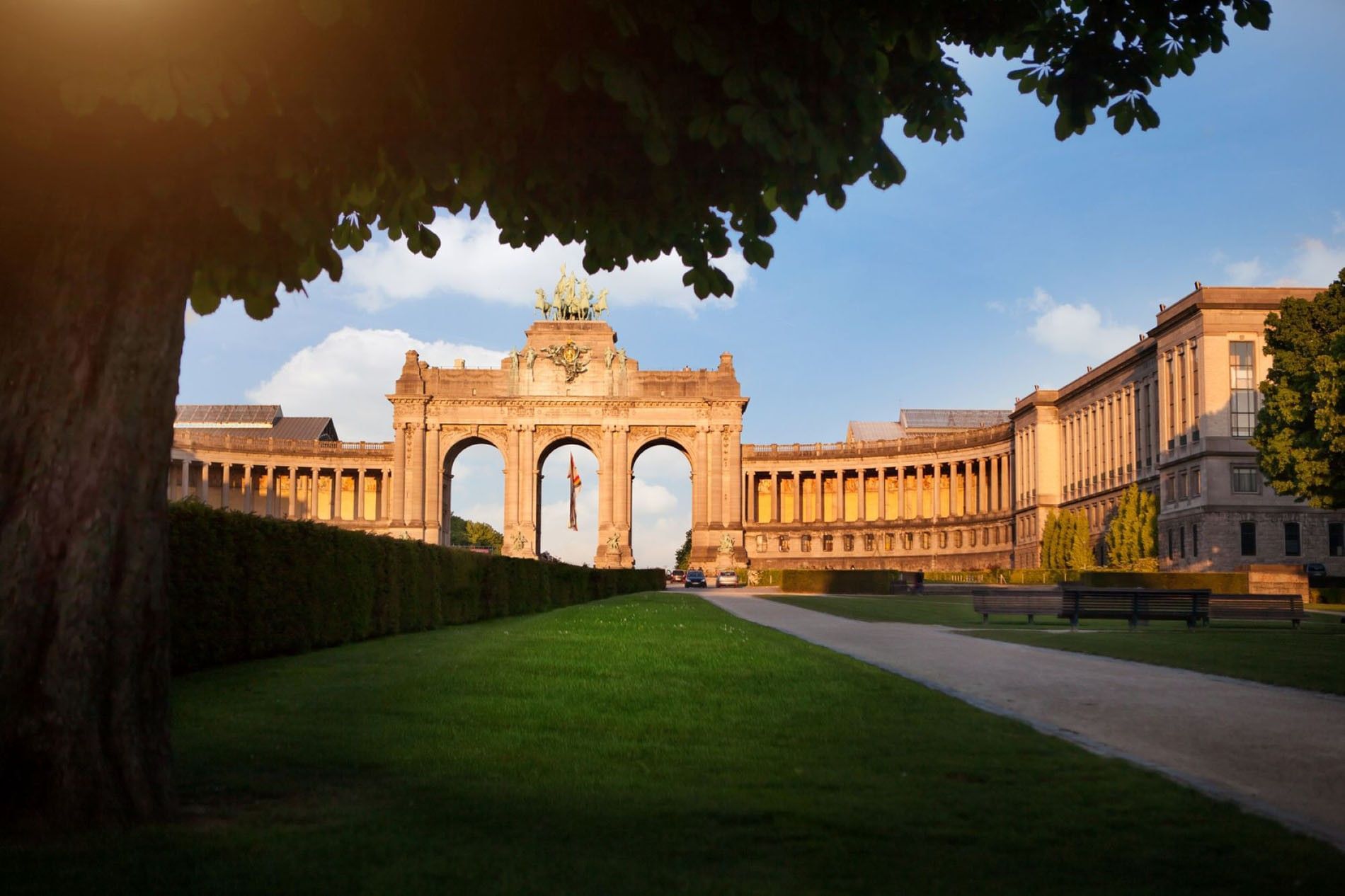 Historic stone archway monument at Cinquentenaire park with lush greenery near Warwick Grand Place Brussels