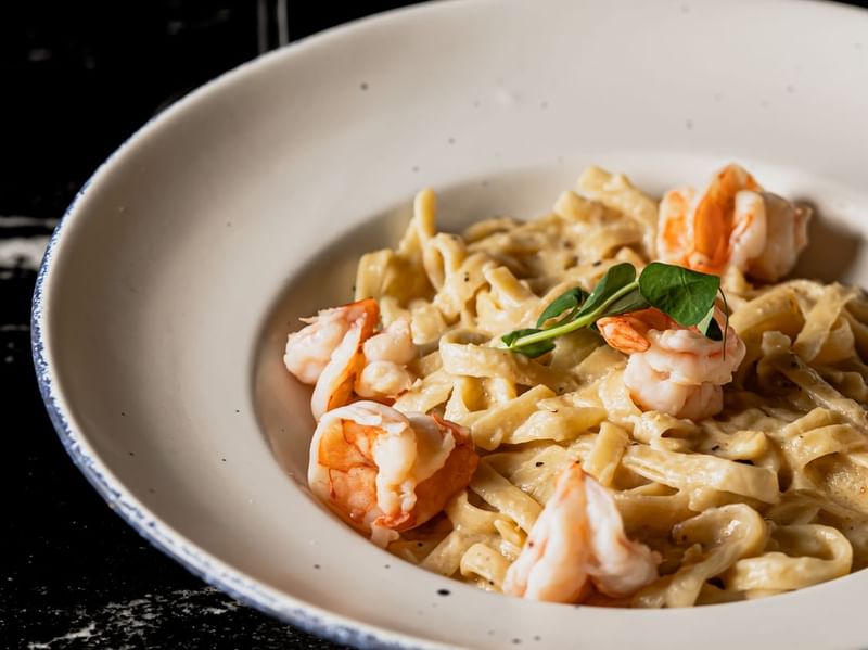 Creamy pasta topped with succulent shrimp and fresh greens, served in a bowl at Los Canarios, Fiesta Americana Travelty