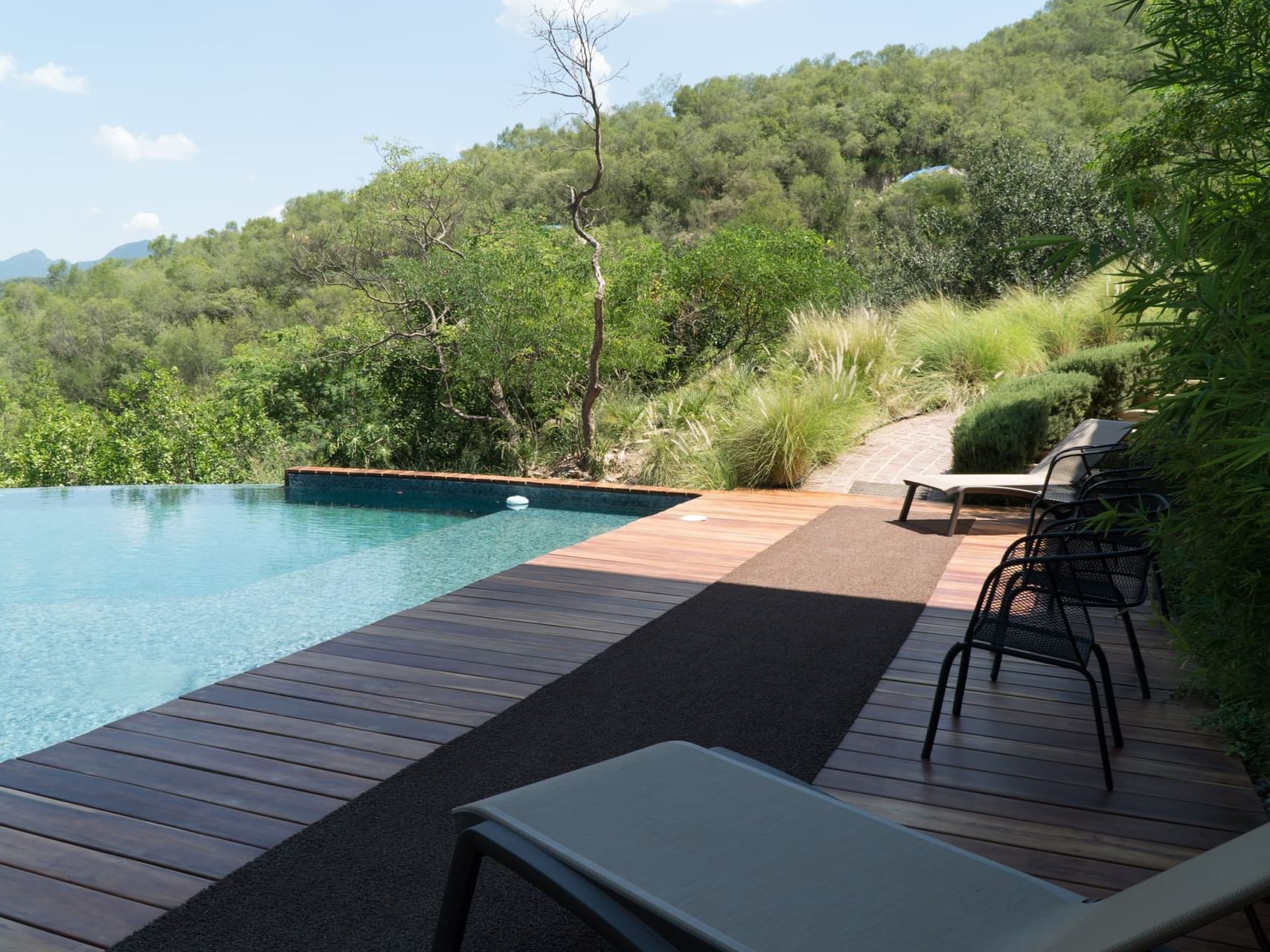 Modern pool area with chairs around in shade at Gamma Hotels