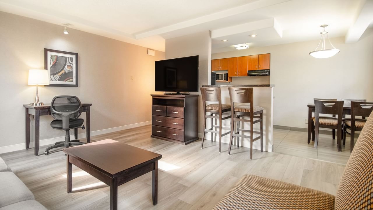 Hotel suite living area with TV, dining tables, couch, work desk and chair