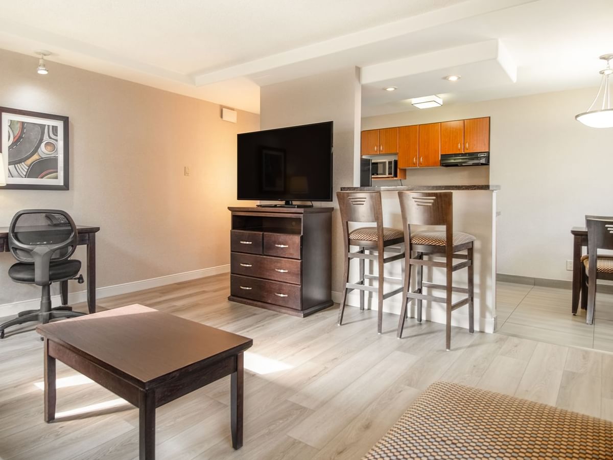Hotel suite living area with TV, dining tables, couch, work desk and chair