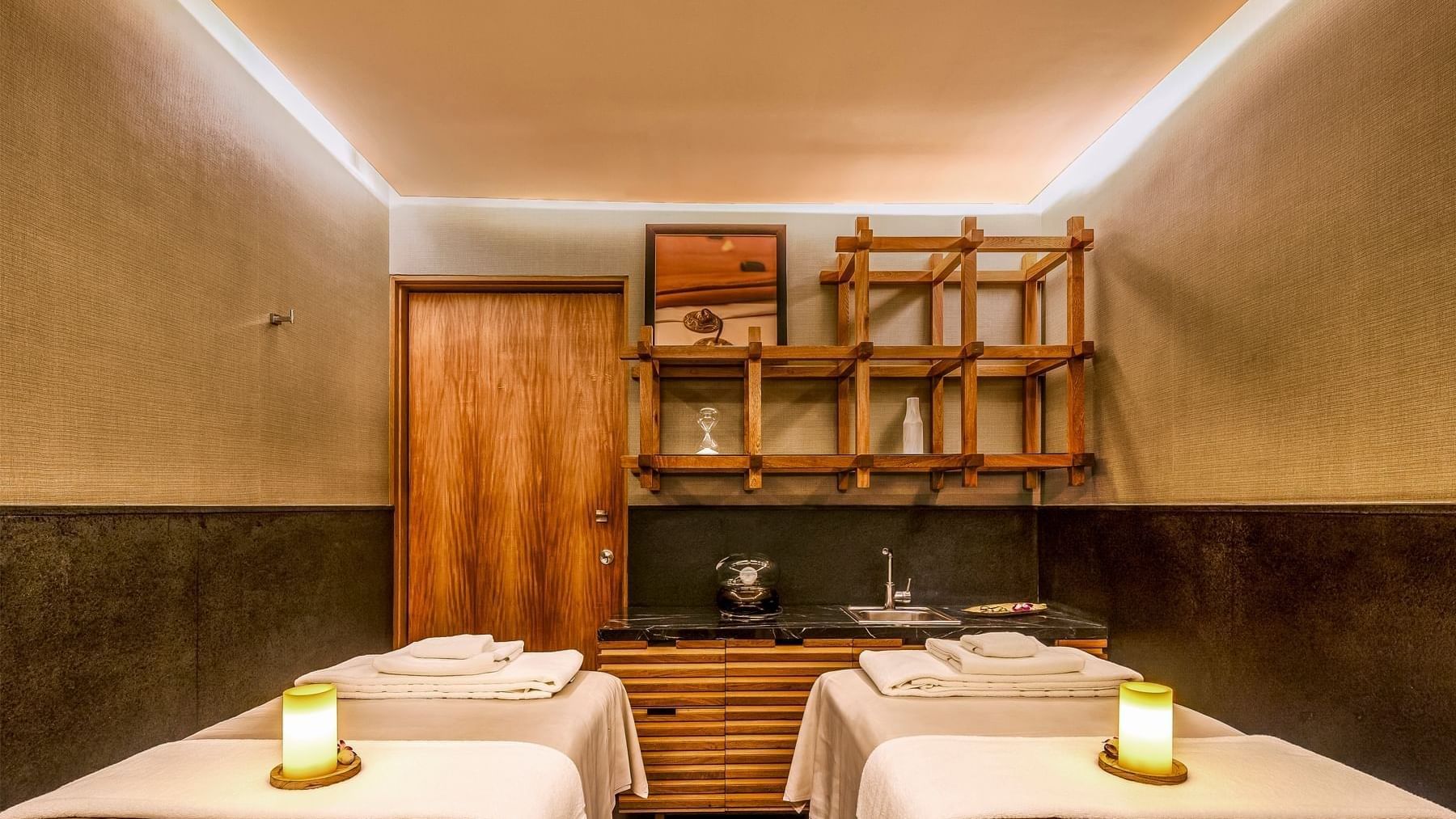 Sala de masajes con tres camas y decoración cálida en el spa del hotel