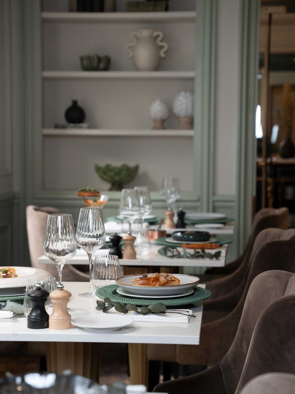 Table setting with crystal wine glasses beside white plates under ambient light at Hotel Westminster Paris