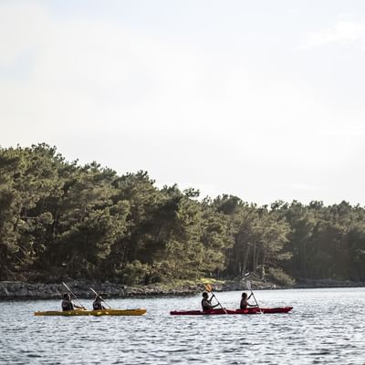 People on kayaking on a lake near Falkensteiner Hotels