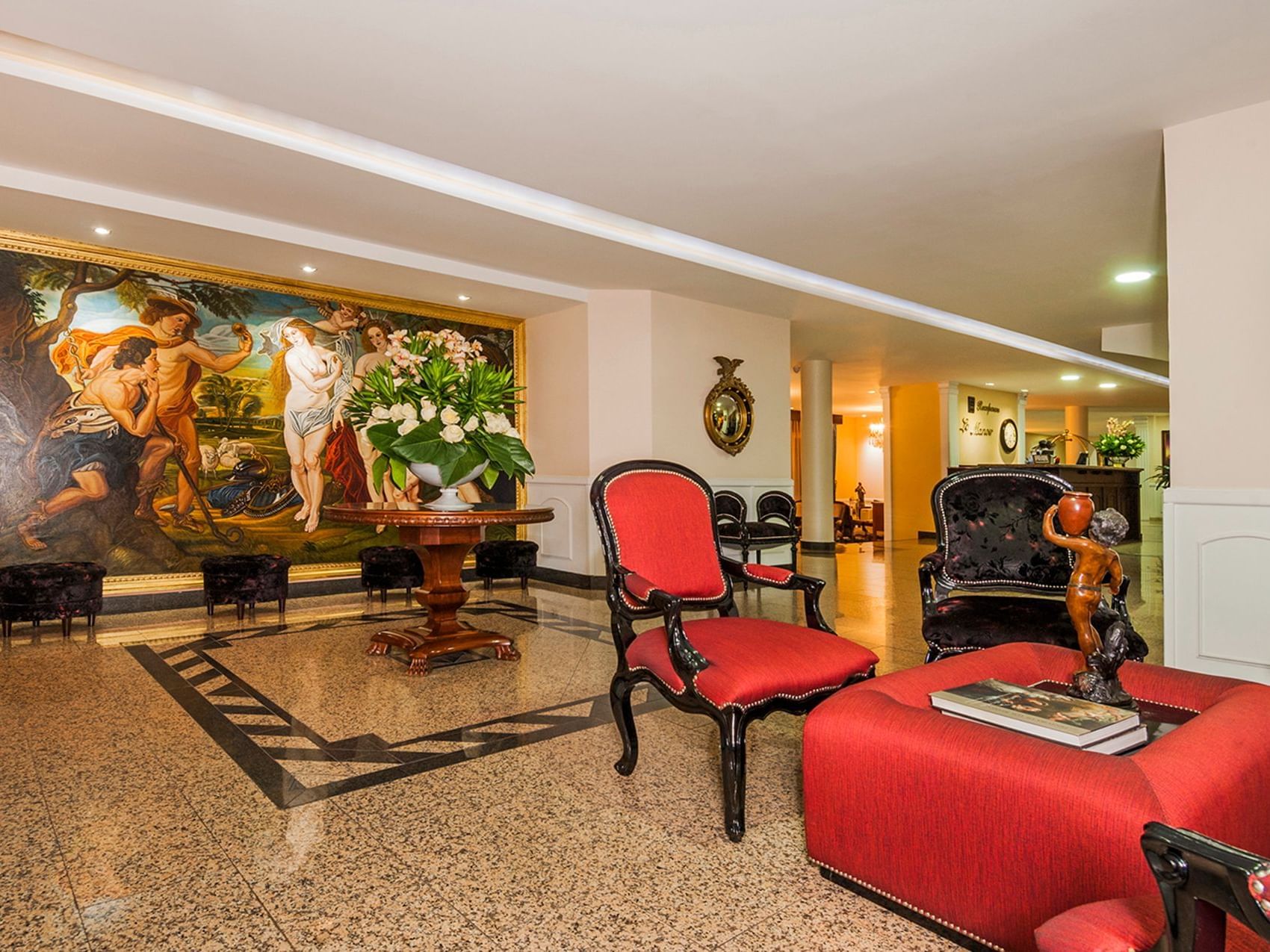 Lobby lounge area with a painting on the wall and red chairs at Le Manoir Bogotá Hotel