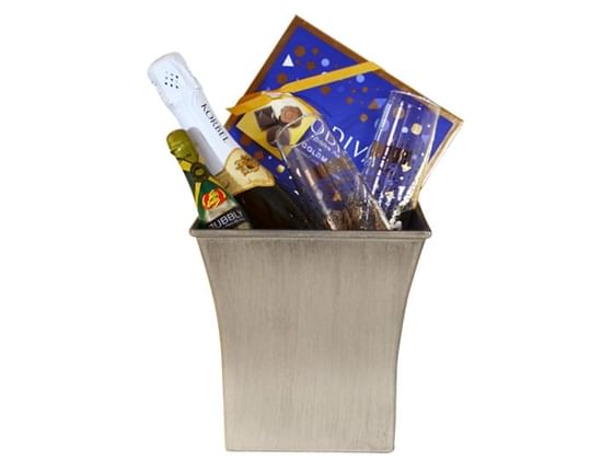 A silver bucket containing Champagne, glasses and box of chocolate