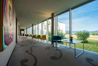 Modern hallway with colorful chairs and scenic outdoor view at Starling Hotel Lausanne