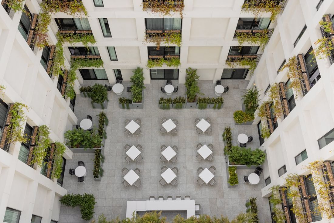 An aerial view of a white building's courtyard with outdoor seating and plants.