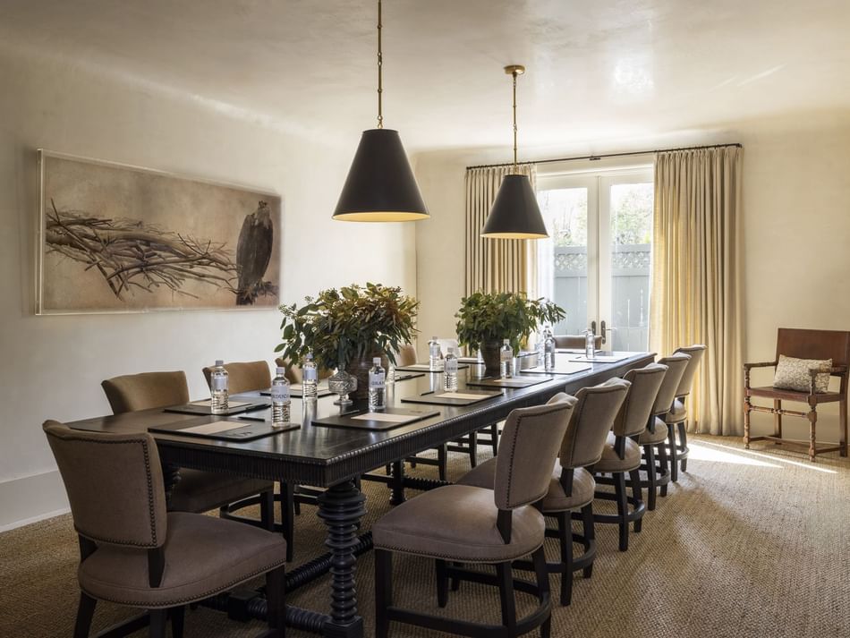The Hawthorn Room at Granduca Houston with a long table, large windows, stylish chairs, and pendant lights