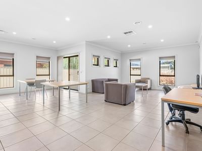Brightly lit room with several desks and couches at La Trobe University Regional Housing – Mildura.