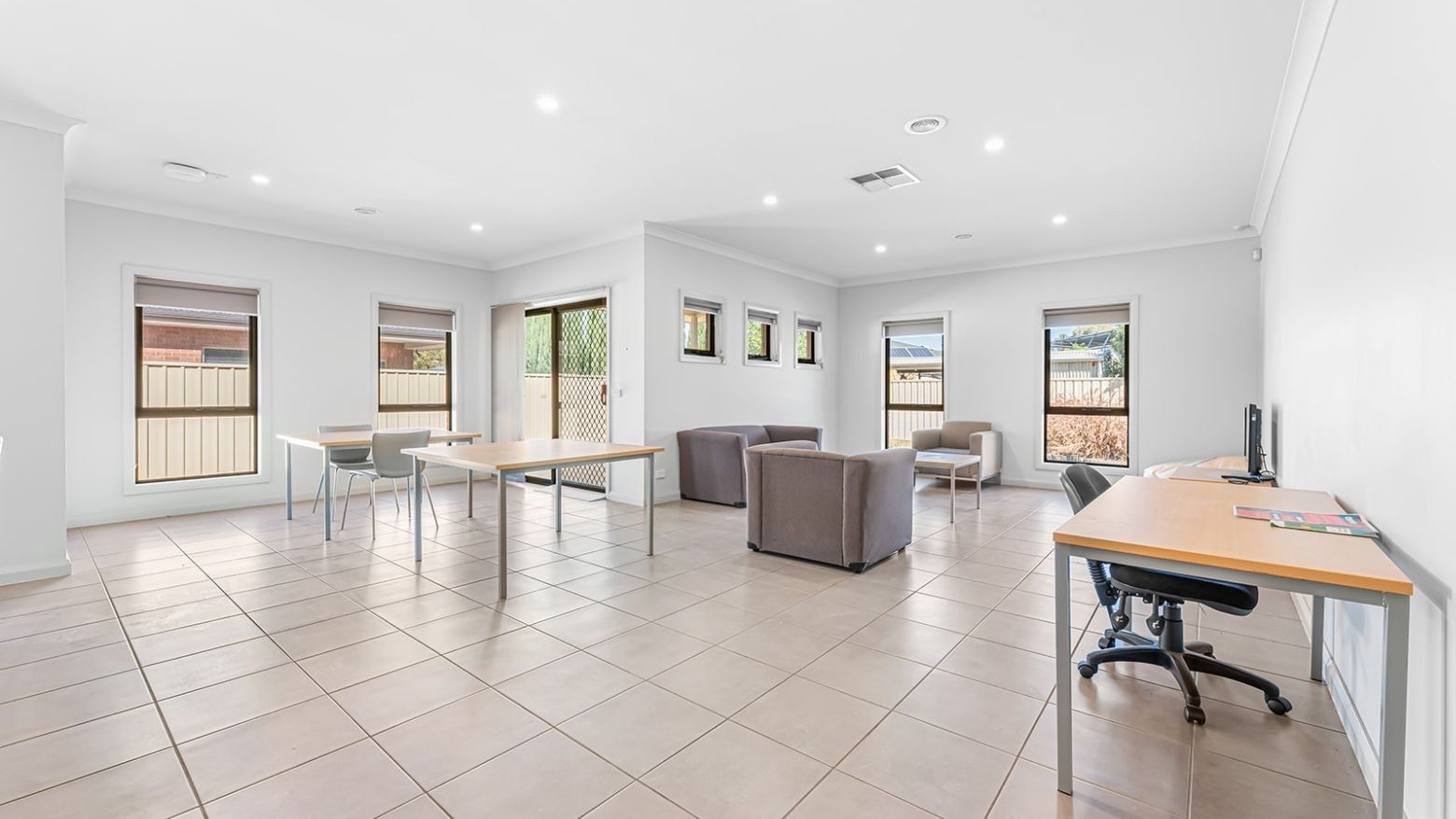 Brightly lit room with several desks and couches at La Trobe University Regional Housing – Mildura.