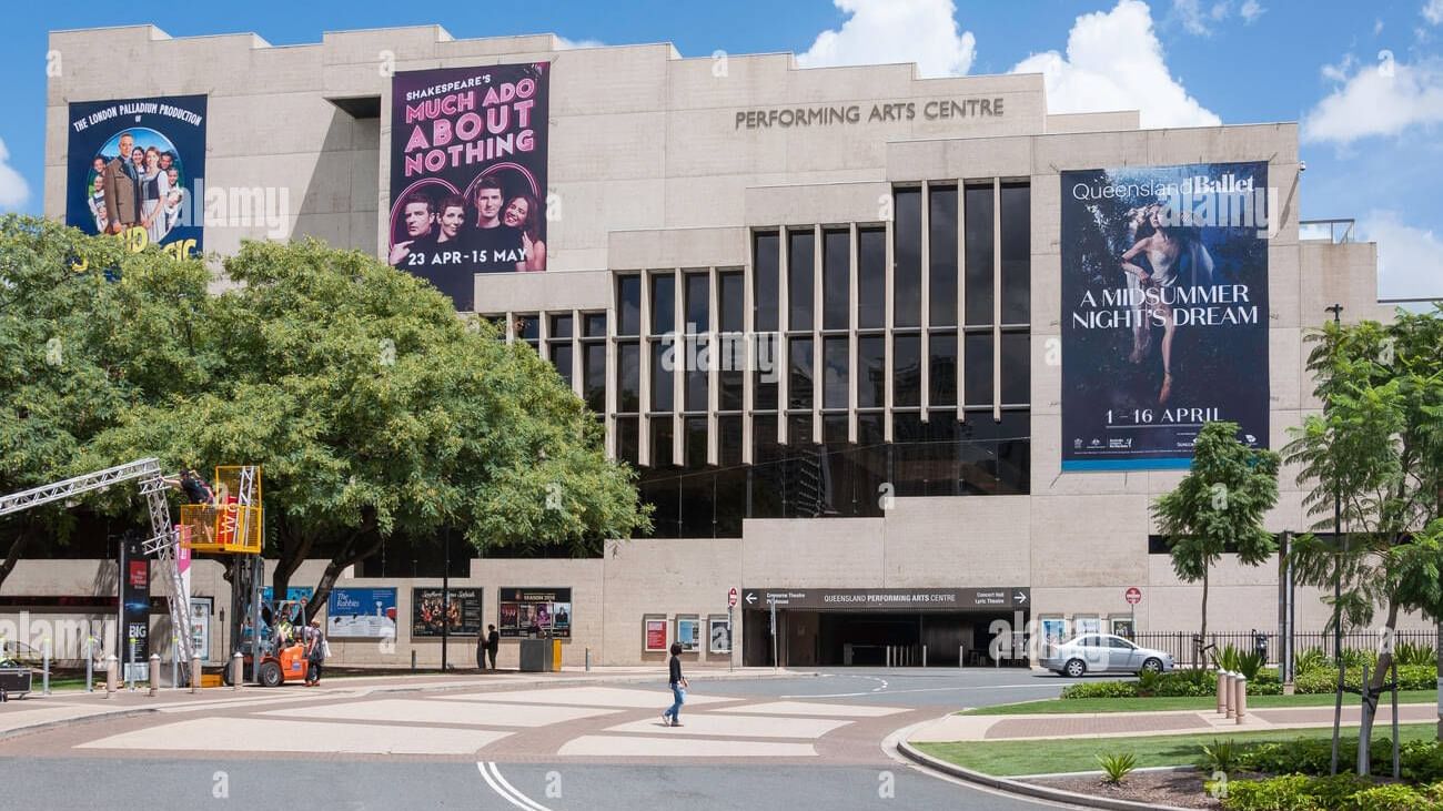 Exterior of the Queensland Performing Arts Centre building with large show banners under a blue sky near The Sebel Brisbane