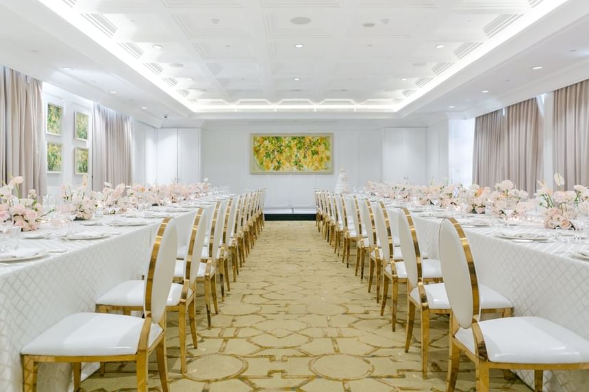 Elegant dining room with long tables adorned with floral centerpieces and gold-accented chairs at Park Hyatt Saigon
