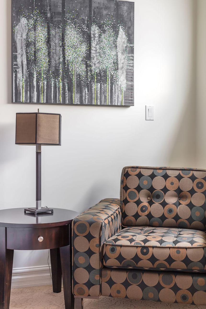 dotted chair with end table beside with lamp and artwork on wall