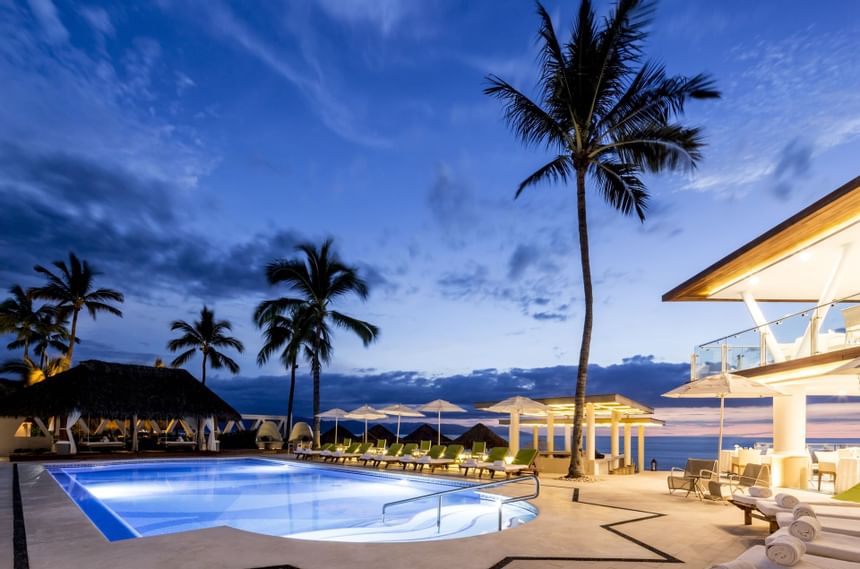 palm trees surround a beachfront pool