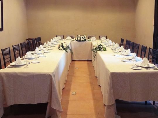 Long table set for an event with chairs and floral arrangements at Quinta Real Puebla in Heroica Puebla de Zaragoza.