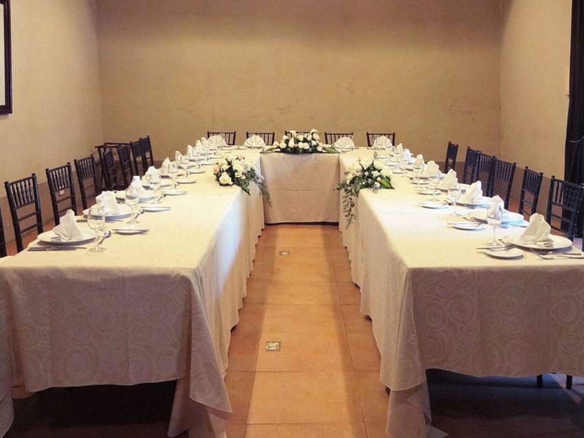 Long table set for an event with chairs and floral arrangements at Quinta Real Puebla in Heroica Puebla de Zaragoza.