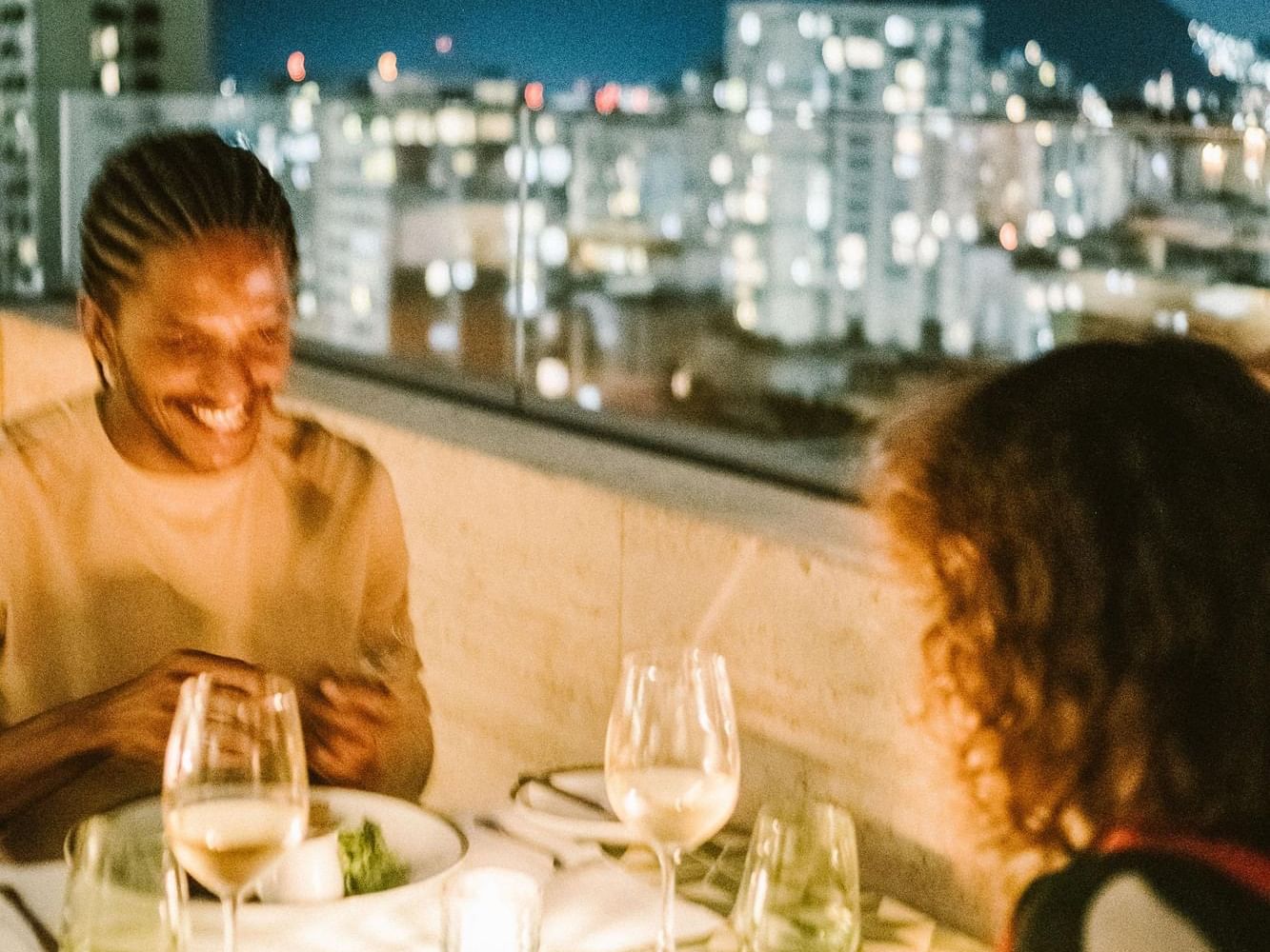 Couple enjoying a romantic dinner on the rooftop overlooking the city at Janeiro Hotel