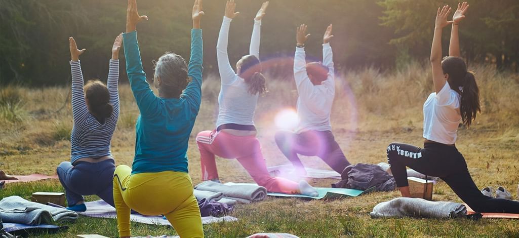 Group of people practicing yoga outdoors on a grassy field