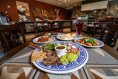 Main course of grilled steak on a patterned blue plate by a bowl of fresh salad served in Fonda de San Luis at Hotel Mirra