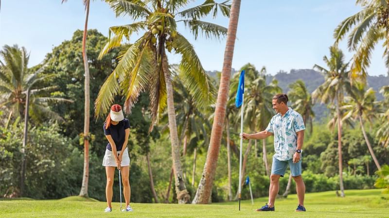 A Couple playing golf in a Golf Course at The Naviti Resort
