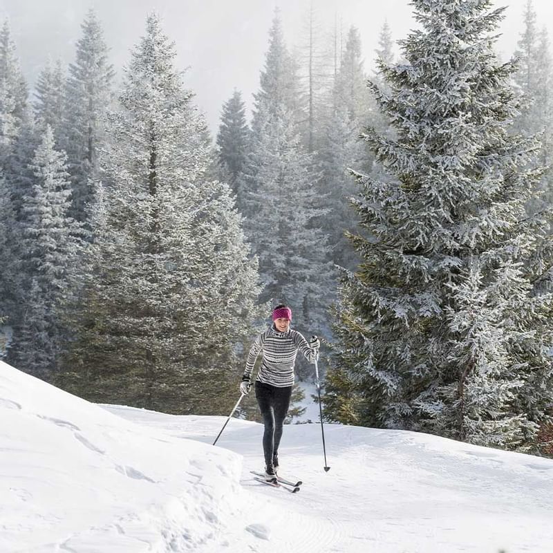 A woman skiing in the woods near Falkensteiner Hotels
