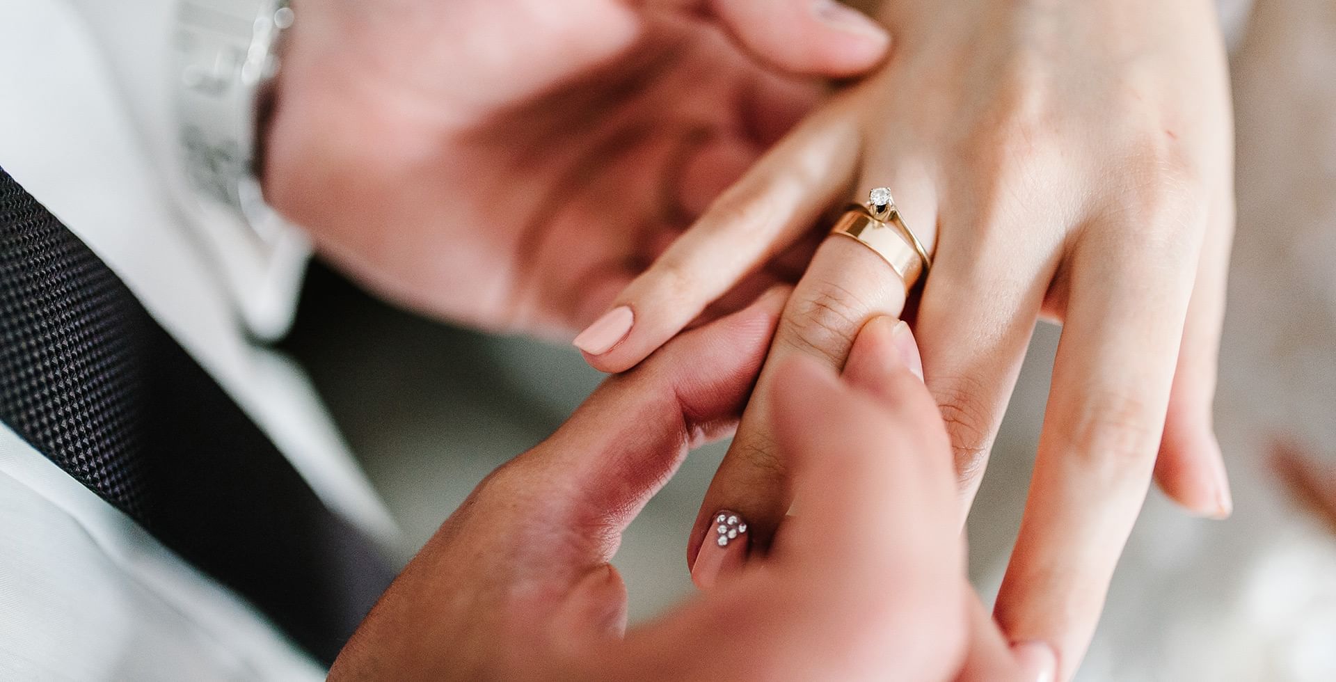 Close-up of the groom placing the wedding ring on bride's finger in a wedding venue at Eldorado, a Coast Hotel