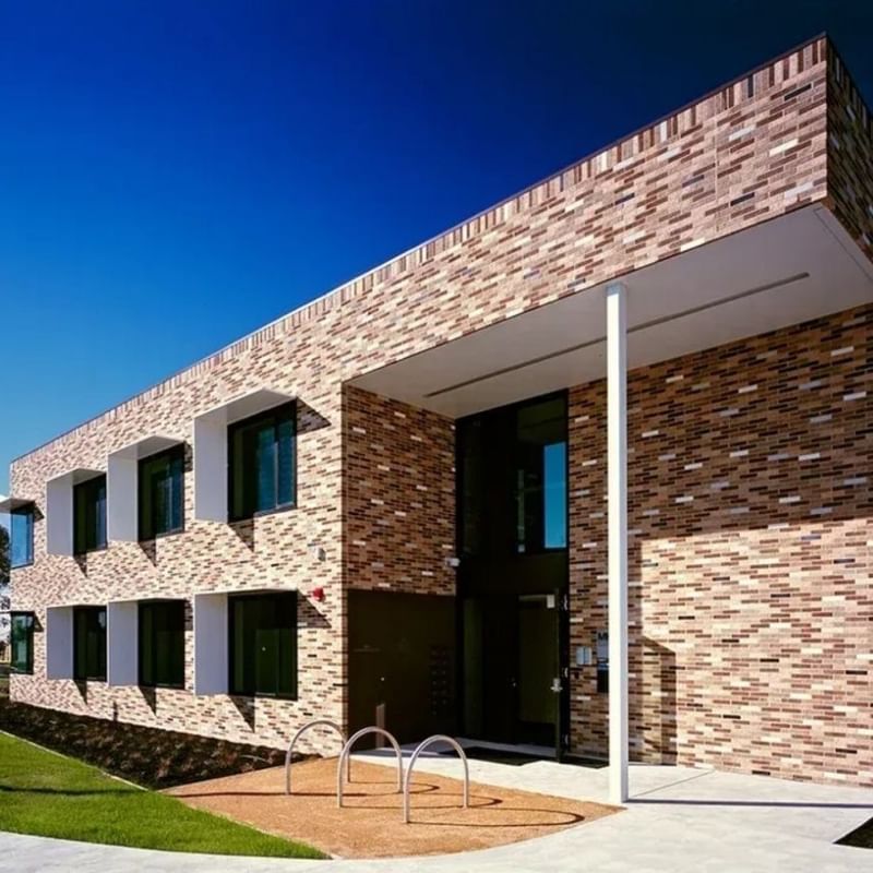 Modern brick building with a blue sky backdrop and a path leading to its entrance at La Trobe University.