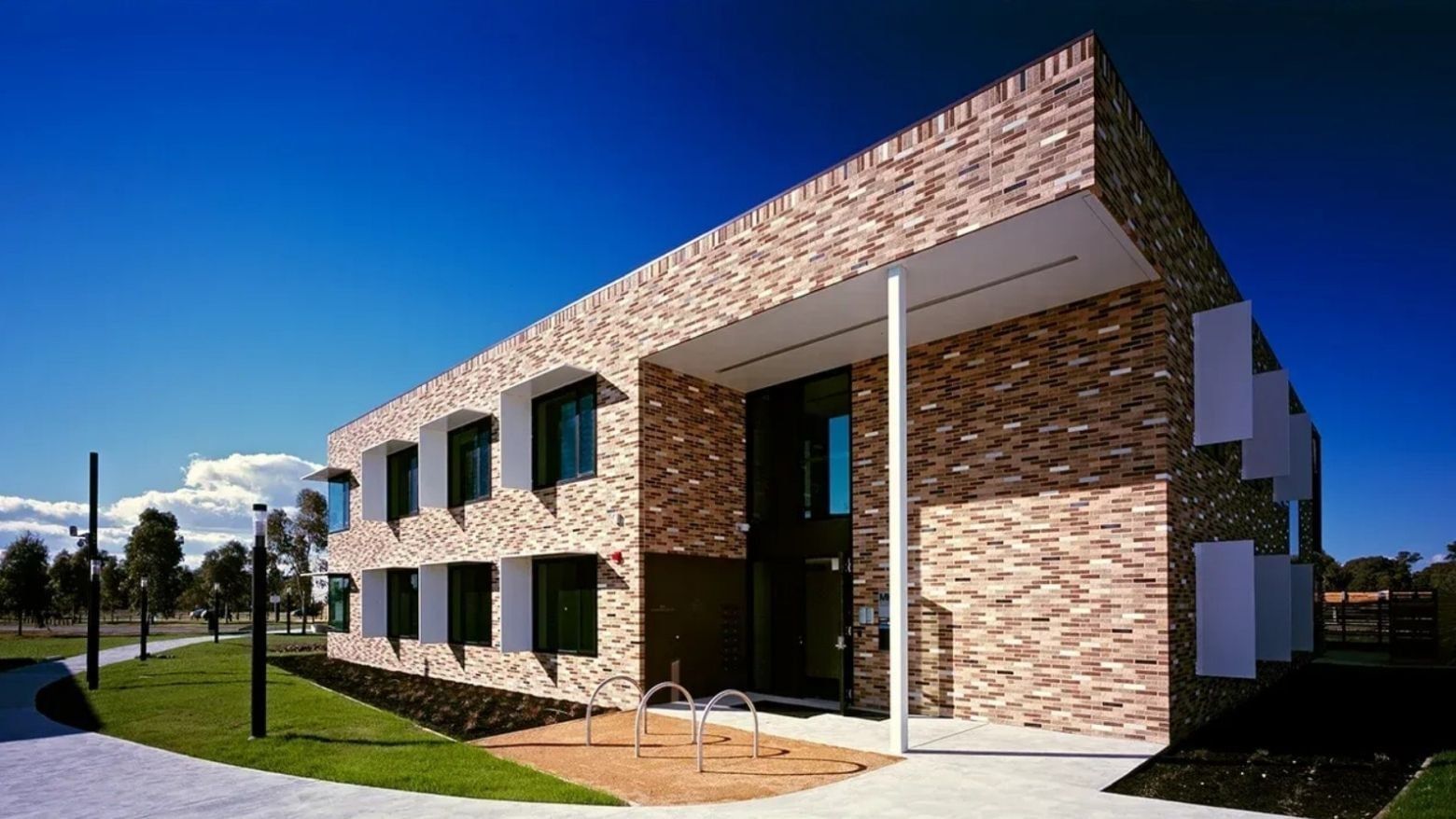 Modern brick building with a blue sky backdrop and a path leading to its entrance at La Trobe University.