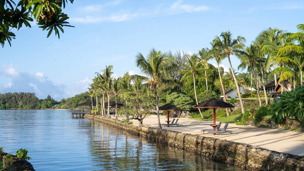 Beachside relaxation area with lounge chairs and umbrellas at Warwick Le Lagon - Vanuatu, Efate.