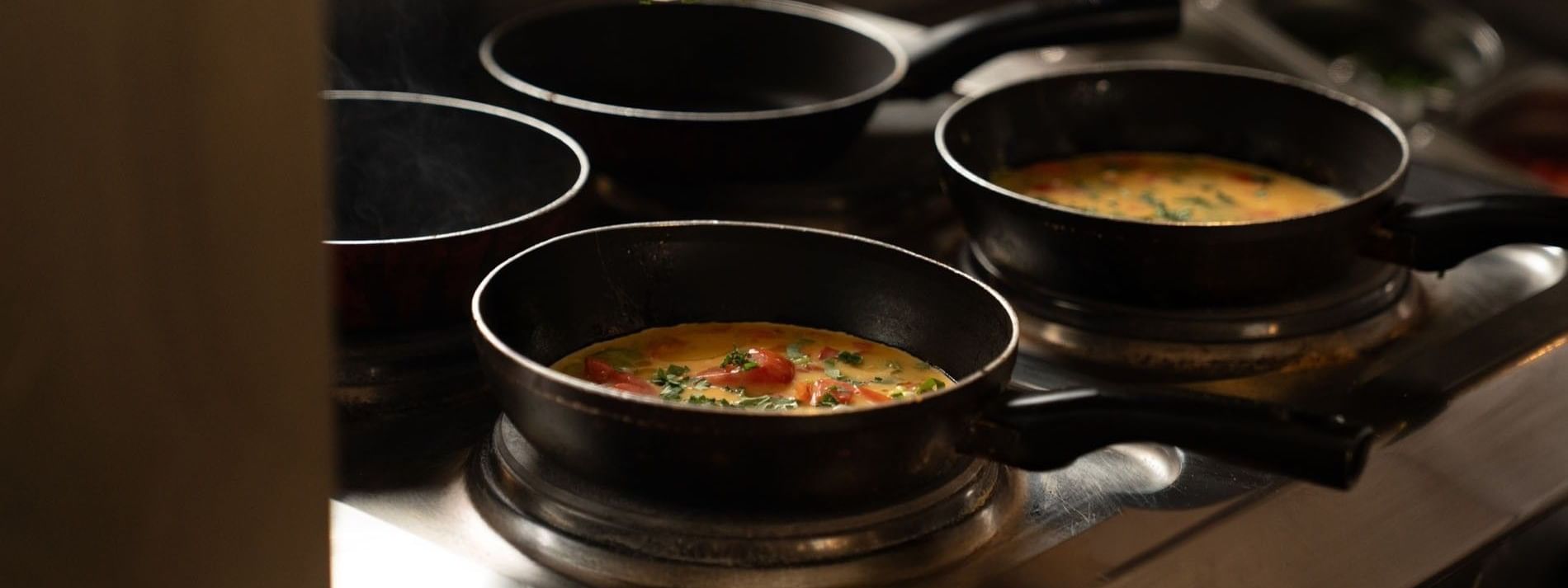 Chef adding fresh green herbs to several small pans in AI Firdous restaurant at Saja Warwick Madinah