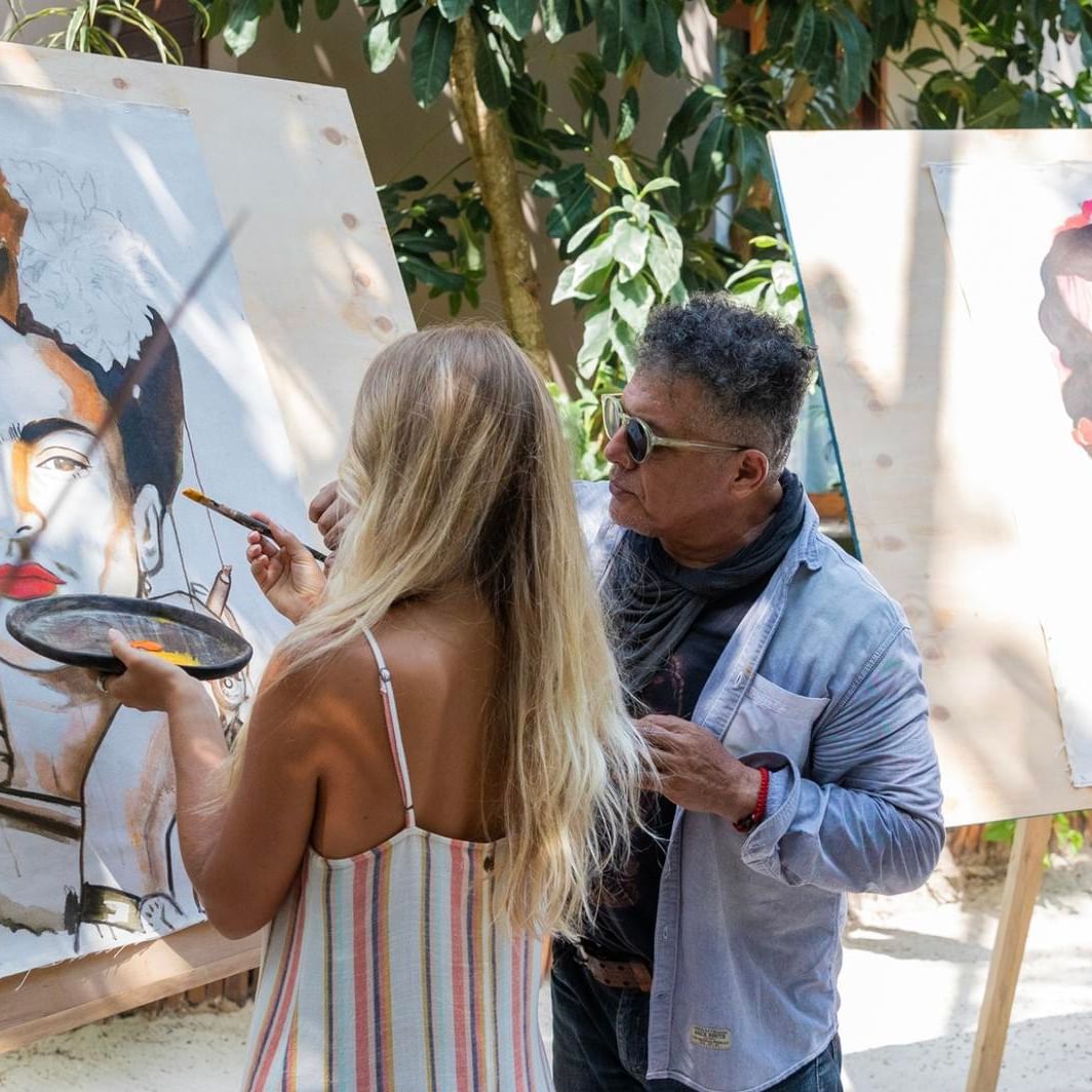 Two guests learn to paint portraits on easels with an instructor at the artistic La Zebra Hotel