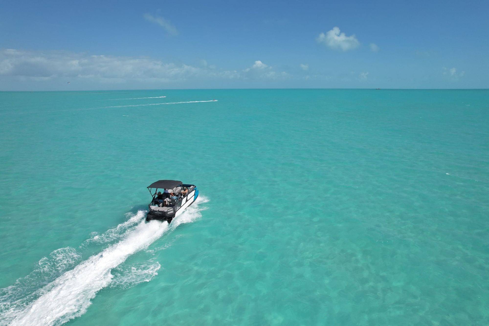 Aerial view of a boat cruising across the turquoise Caicos Banks