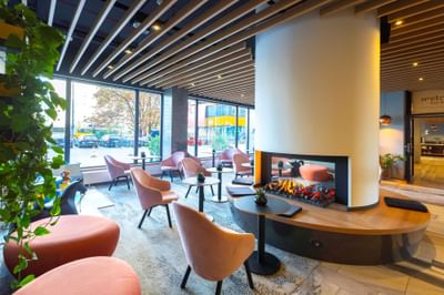 Lobby area with chairs, tables and central fireplace at Metropol Hotel