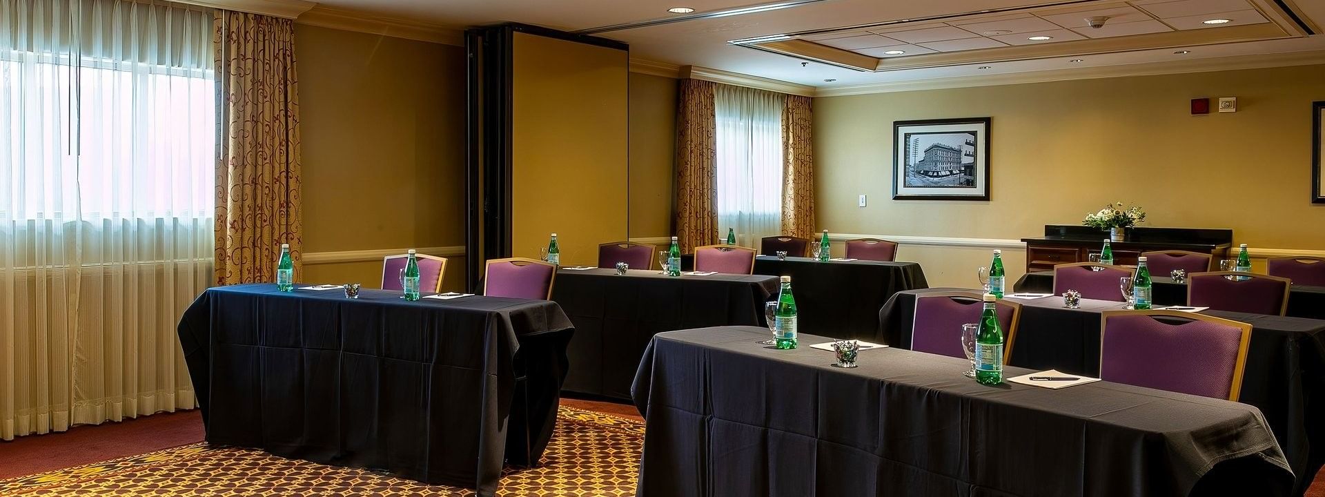 Black clothed tables by purple chairs under recessed lights in Tabor I at Warwick Denver