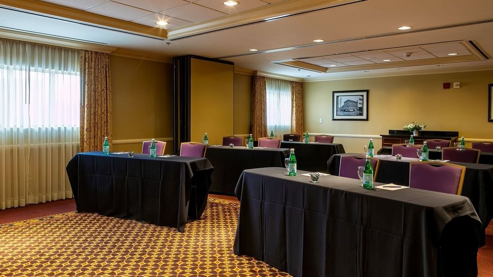 Black clothed tables by purple chairs under recessed lights in Tabor I at Warwick Denver