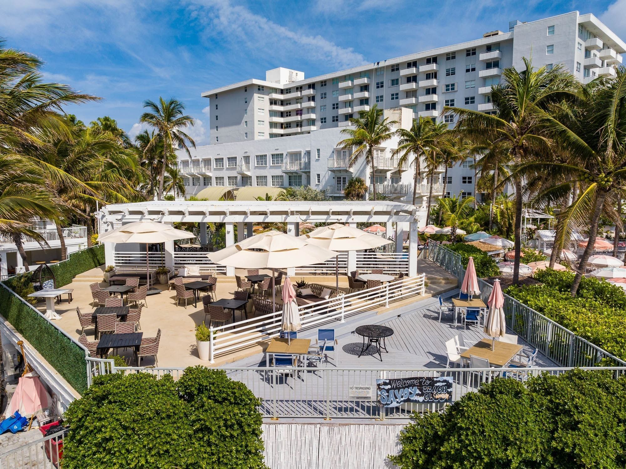 A large white building with balconies and palm trees in front of it.