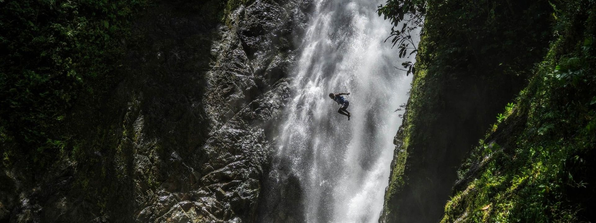 Adventurer diving into a waterfall in lush greenery at Warwick Fiji Resort and Spa in Korolevu