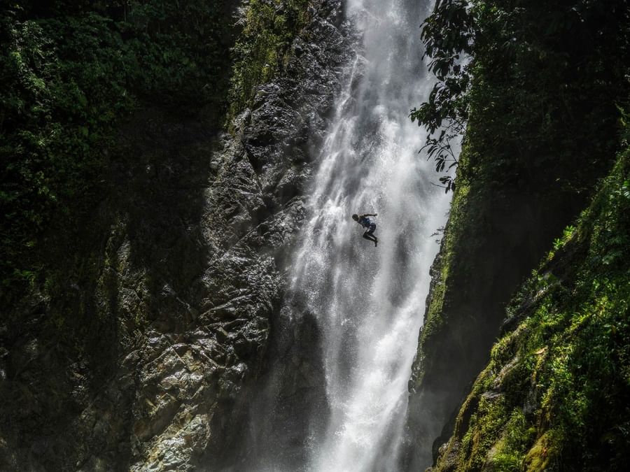 Adventurer diving into a waterfall in lush greenery at Warwick Fiji Resort and Spa in Korolevu