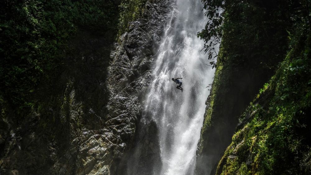 Adventurer diving into a waterfall in lush greenery at Warwick Fiji Resort and Spa in Korolevu.