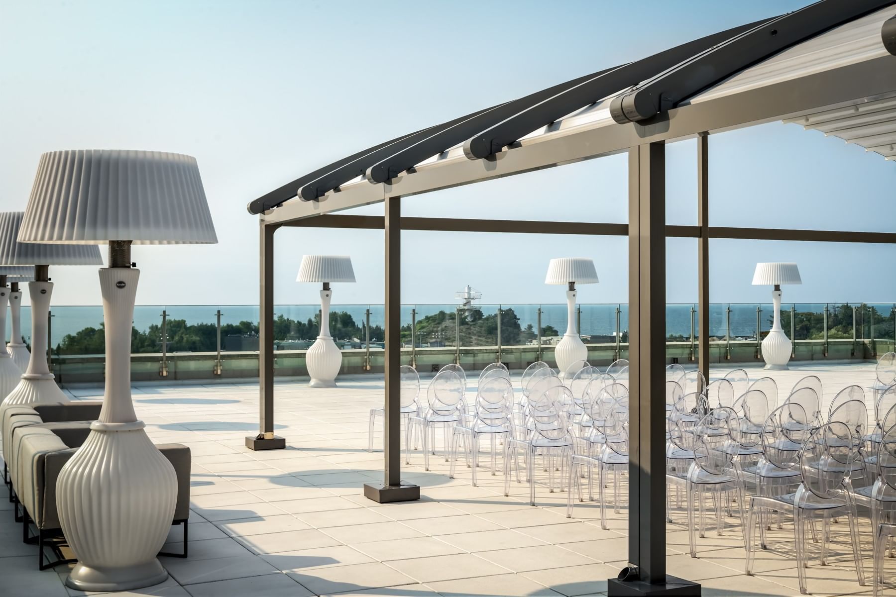 High Park Terrace with clear chairs beneath a modern canopy & oversized white lamps overlooking the water at Hotel X Toronto
