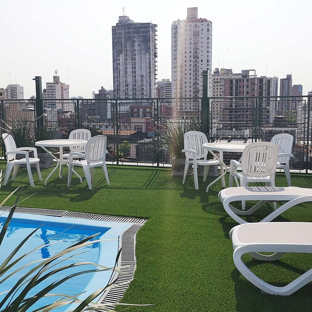 An open-air pool with sun loungers on the rooftop at DOT Hotels