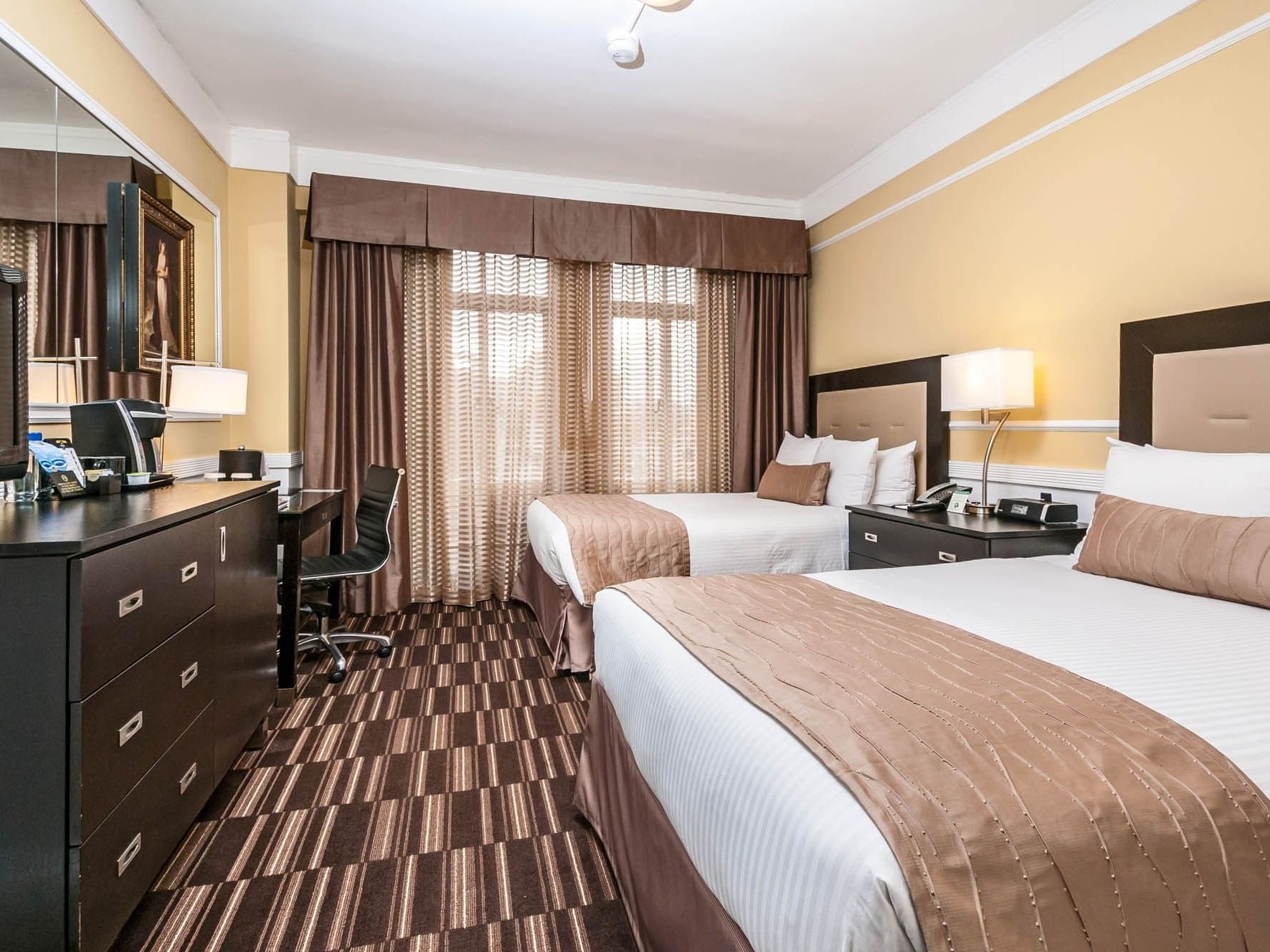 Two beds with white linens and brown bedding in a hotel room at Pickwick San Francisco.
