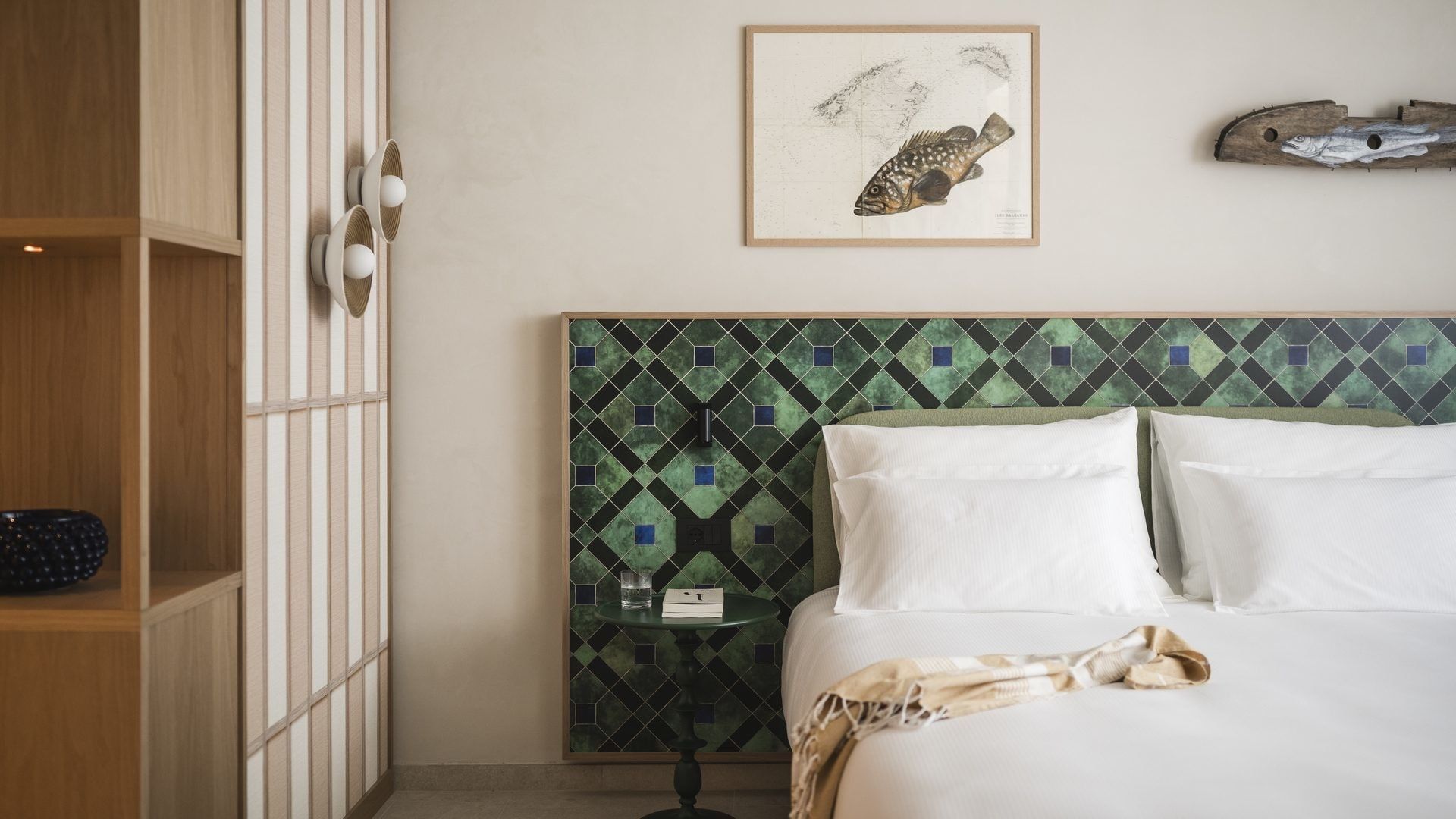 Camera da letto con testiera in mosaico, libri, e un pesce decorato sulla parete.