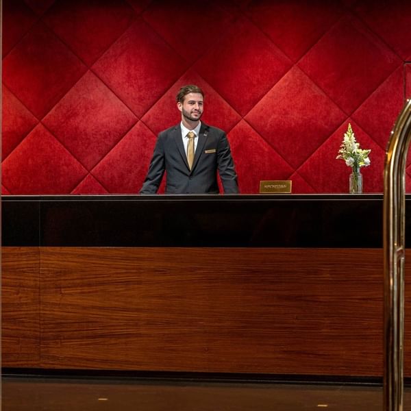 Concierge by a black desk under a red diamond wall, in the lobby at Saja by Warwick Paris Champs Elysées