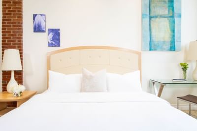 King bed, comfy pillows, work desk with lamp & paintings on the wall in King Premiere Sky at Retro Suites Hotel