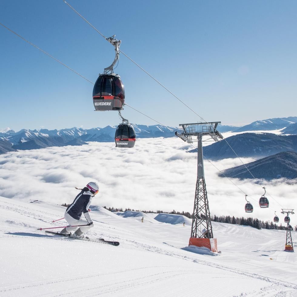 Skifahrerin und Gondelbahn in den Bergen im Rahmen der Dolomiti Springdays-Angebote.