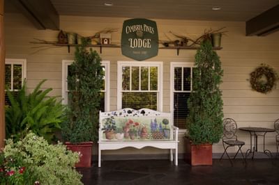 Front porch of Cambria Pines Lodge with seating area and plants