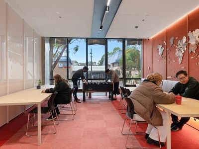 People playing a table game and others working at La Trobe University apartments.